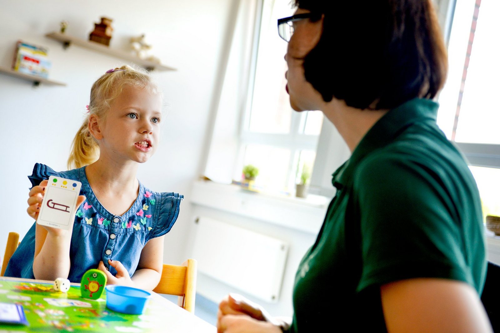 Logopädie Kind Kind und Therapeutin machen Sprechübungen